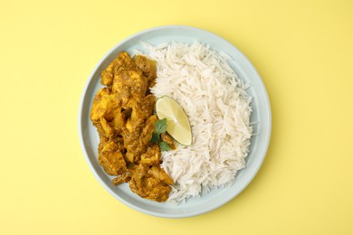 Photo of Delicious chicken curry with rice on yellow background, top view