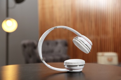 Photo of Stylish headphones on table against blurred background