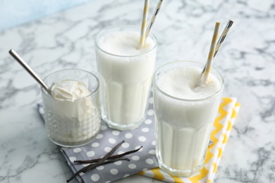 Photo of Glasses with milk shake and tasty vanilla ice cream on light background