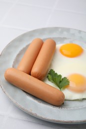 Photo of Delicious boiled sausages, fried eggs and parsley on white table, closeup