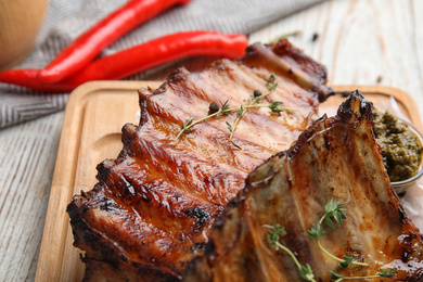 Photo of Tasty grilled ribs with thyme on white wooden table, closeup