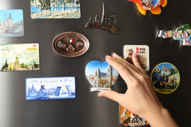 MYKOLAIV, UKRAINE - DECEMBER 25, 2018: Woman putting magnet on fridge door, closeup