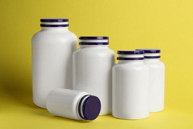 Photo of Many closed medicine bottles on yellow background