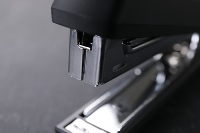 Photo of One black stapler on gray background, closeup