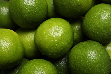 Photo of Fresh ripe limes with water drops as background, closeup