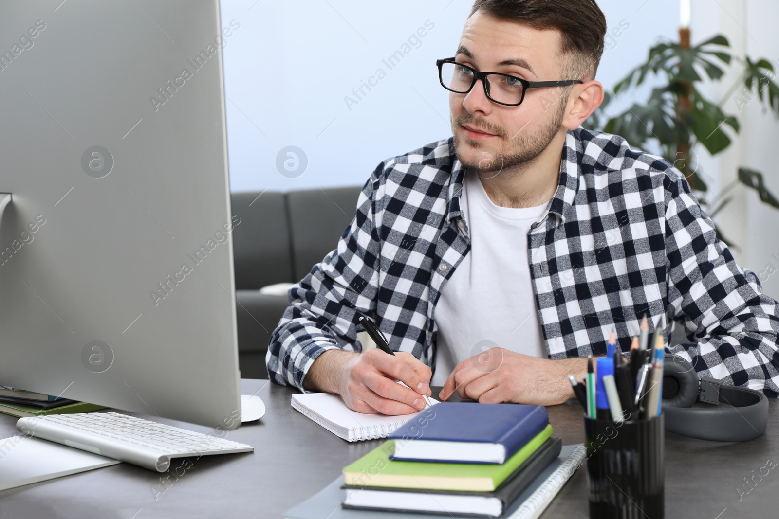 Photo of Young man using modern computer for studying at home. Distance learning
