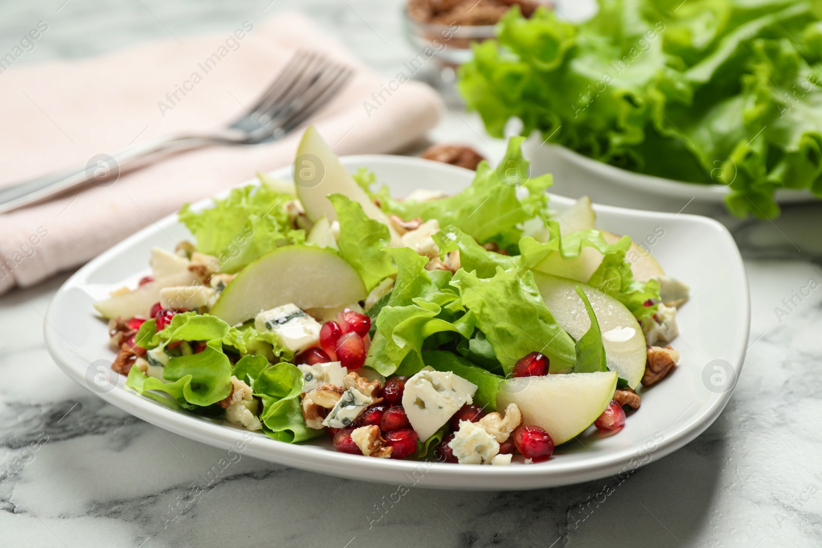 Photo of Tasty salad with pear slices on white marble table, closeup