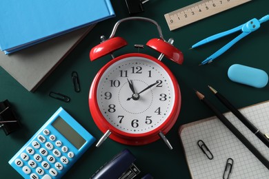 Photo of Flat lay composition with alarm clock and different stationery on green background. School time