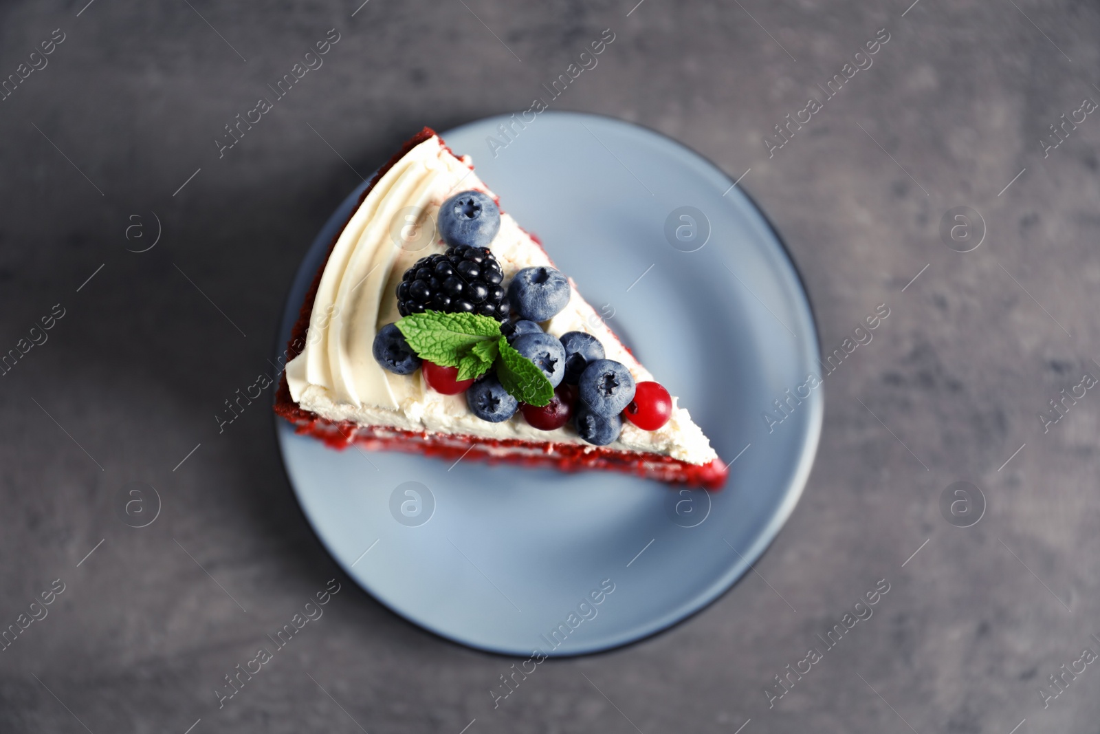 Photo of Plate with piece of delicious homemade red velvet cake on gray background, top view