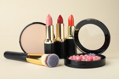 Photo of Different luxury decorative cosmetics and brush on beige background