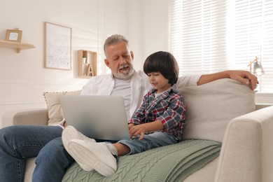 Photo of Grandfather and grandson using laptop together at home