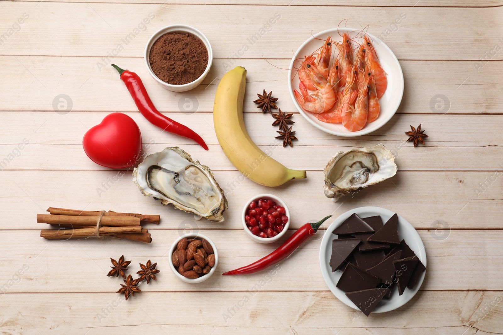 Photo of Natural aphrodisiac. Different food products and red decorative heart on light wooden table, flat lay