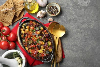 Dish with tasty ratatouille, ingredients and bread on grey textured table, flat lay. Space for text