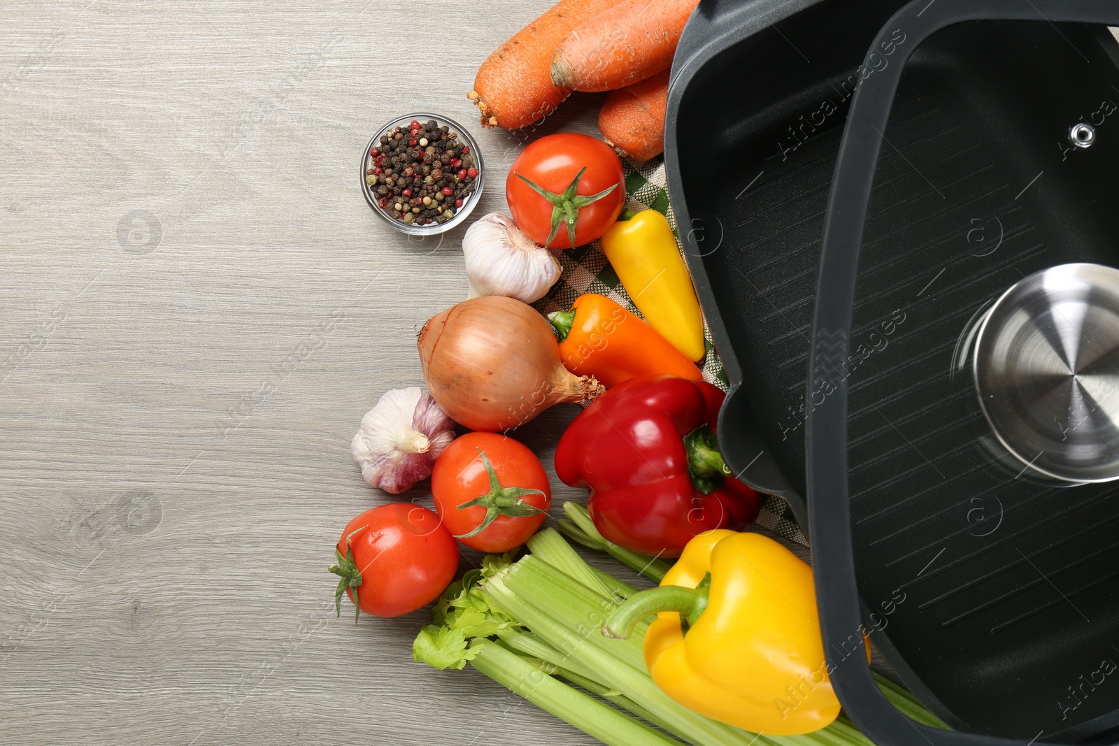 Photo of Black pot, lid and fresh products on wooden table, top view. Space for text