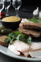 Tasty salt pork with rye bread served on table, closeup