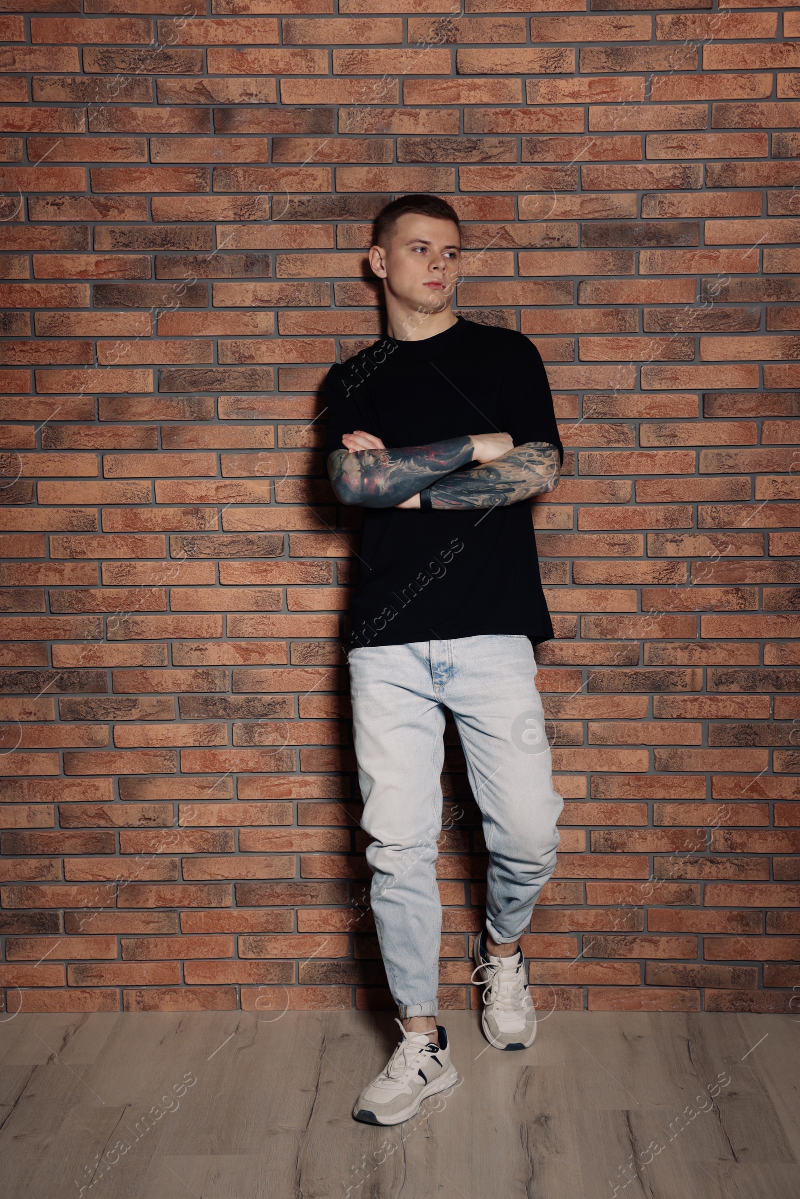 Photo of Young man with tattoos near brick wall