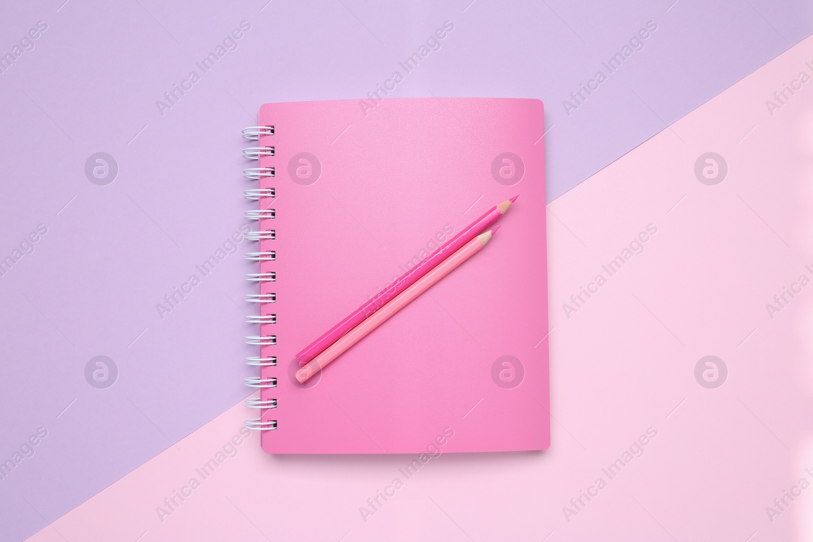 Photo of Pink notebook and pencils on color background, top view