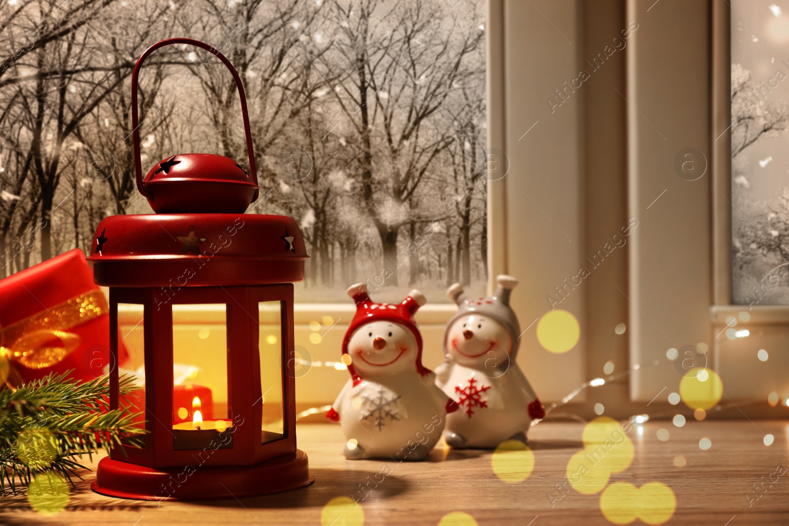 Image of Red Christmas lantern with burning candle and festive decor on window sill indoors 