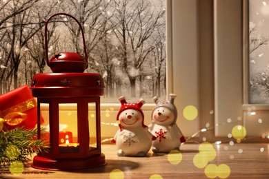 Image of Red Christmas lantern with burning candle and festive decor on window sill indoors 