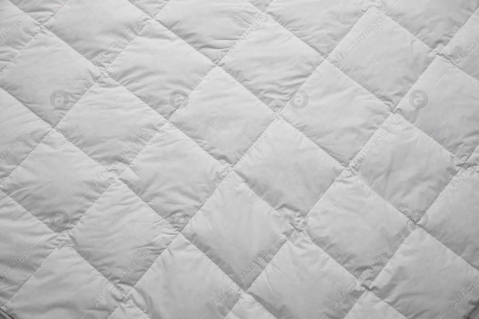 Photo of Soft quilted blanket as background, top view