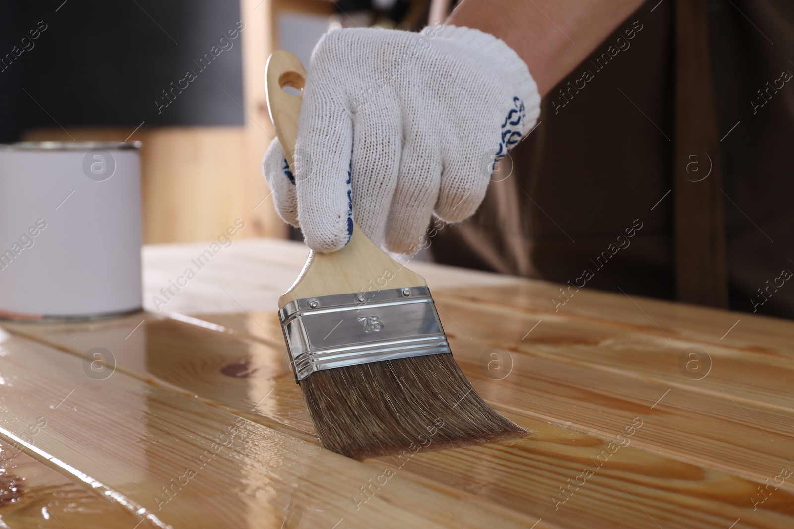 Photo of Man varnishing wooden surface with brush, closeup