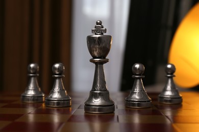 Photo of King and pawn pieces on chessboard indoors
