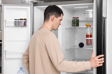 Photo of Man near empty refrigerator in kitchen at home