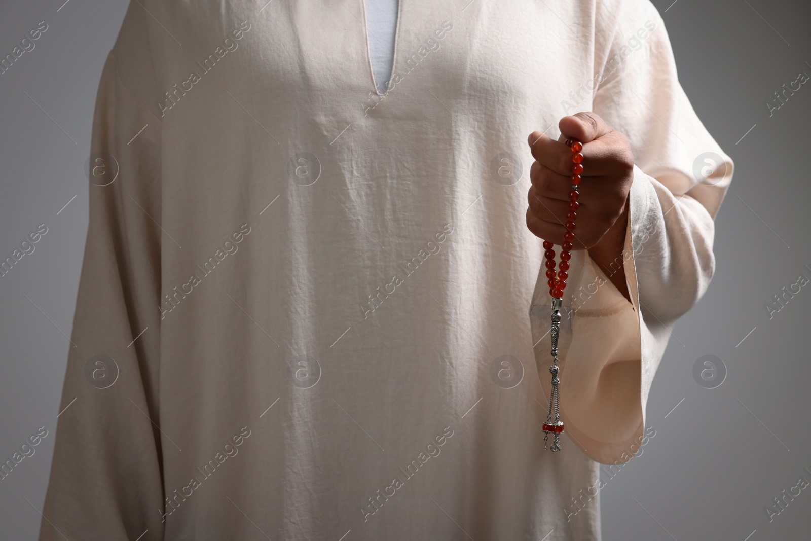 Photo of Muslim man with misbaha on light grey background, closeup