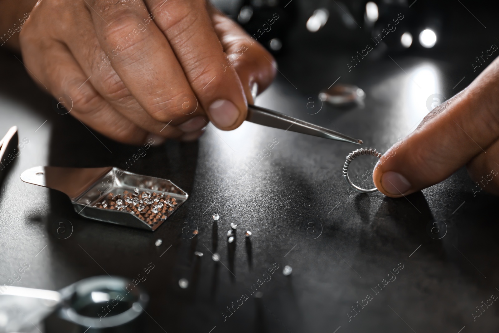 Photo of Male jeweler examining diamond ring in workshop, closeup view