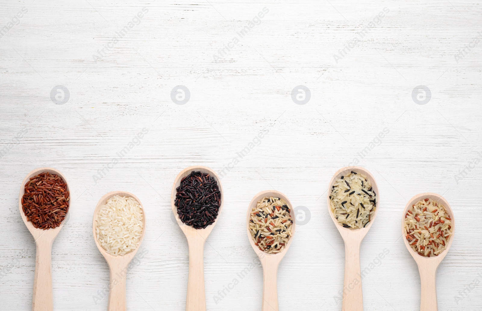 Photo of Flat lay composition with brown and polished rice on white wooden table. Space for text