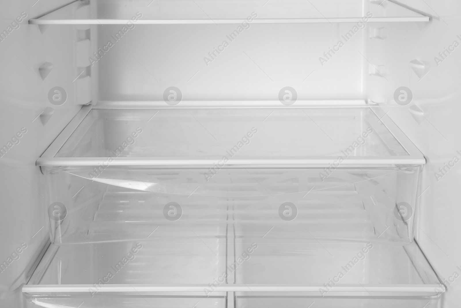 Photo of Modern open refrigerator with empty shelves, closeup