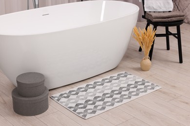 Photo of Soft bath mat, towels and boxes in bathroom