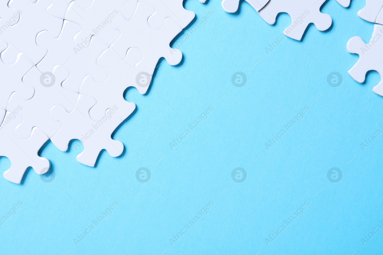 Photo of Blank white puzzle pieces on light blue background, flat lay. Space for text