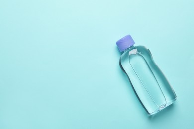 Photo of Bottlebaby oil on turquoise background, top view. Space for text