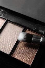 Photo of Beautiful eye shadow palette with brush on grey table, closeup