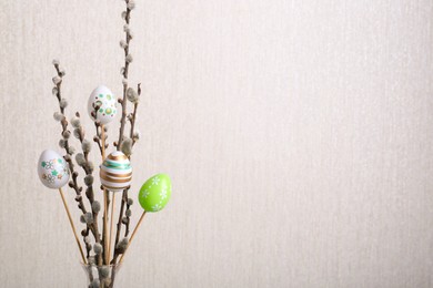 Photo of Beautiful willow branches with painted eggs on light grey background, space for text. Easter decor