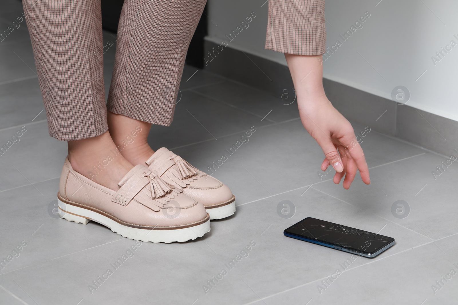 Photo of Woman taking dropped smartphone from floor, closeup. Device repairing