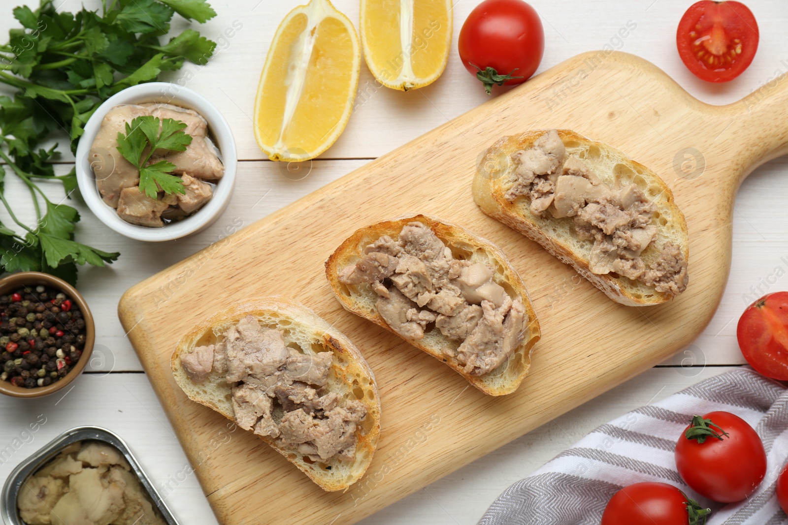 Photo of Tasty sandwiches with cod liver on white wooden table, flat lay