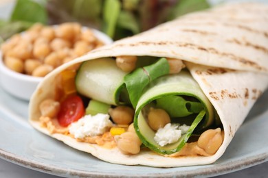 Delicious hummus wrap with vegetables on table, closeup