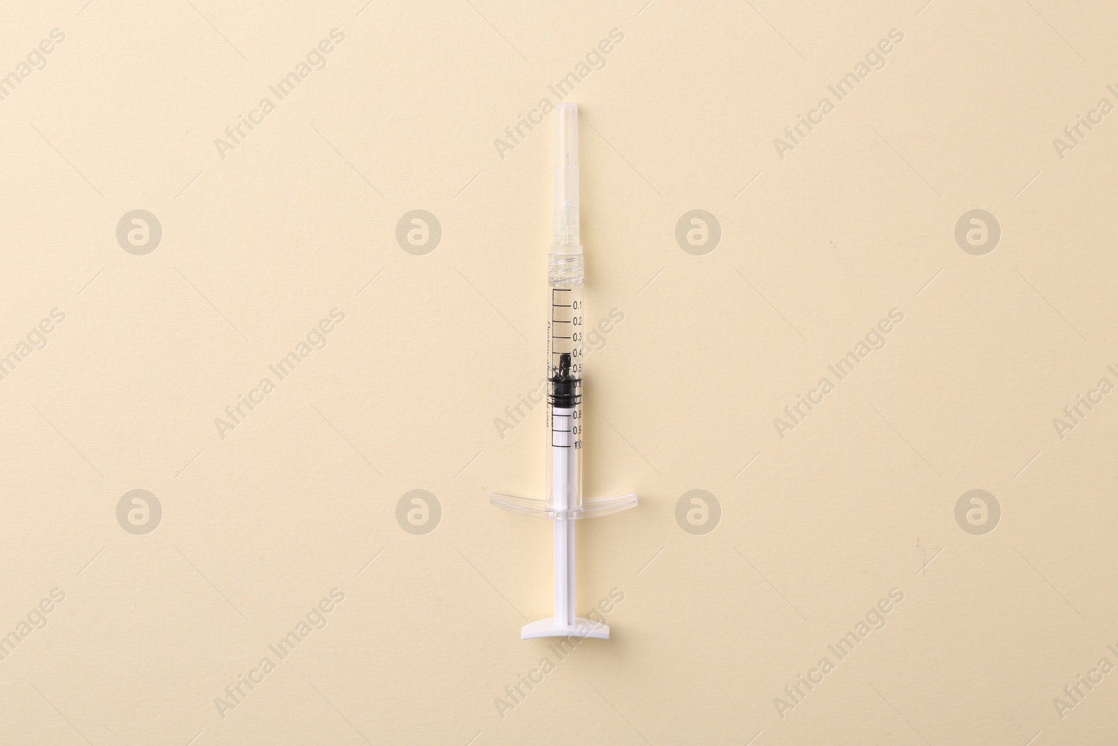 Photo of Injection cosmetology. One medical syringe on beige background, top view