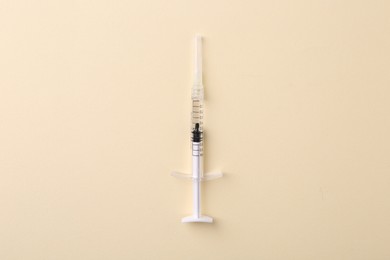 Injection cosmetology. One medical syringe on beige background, top view
