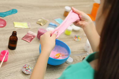 Little girl making DIY slime toy at table, closeup