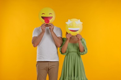 Photo of People covering faces with emoticons on yellow background