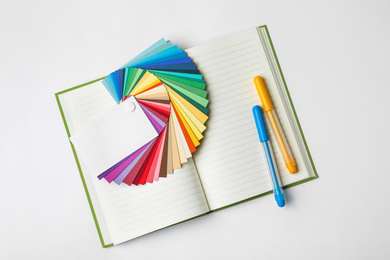 Photo of Color palette, pens and notebook on white background, top view