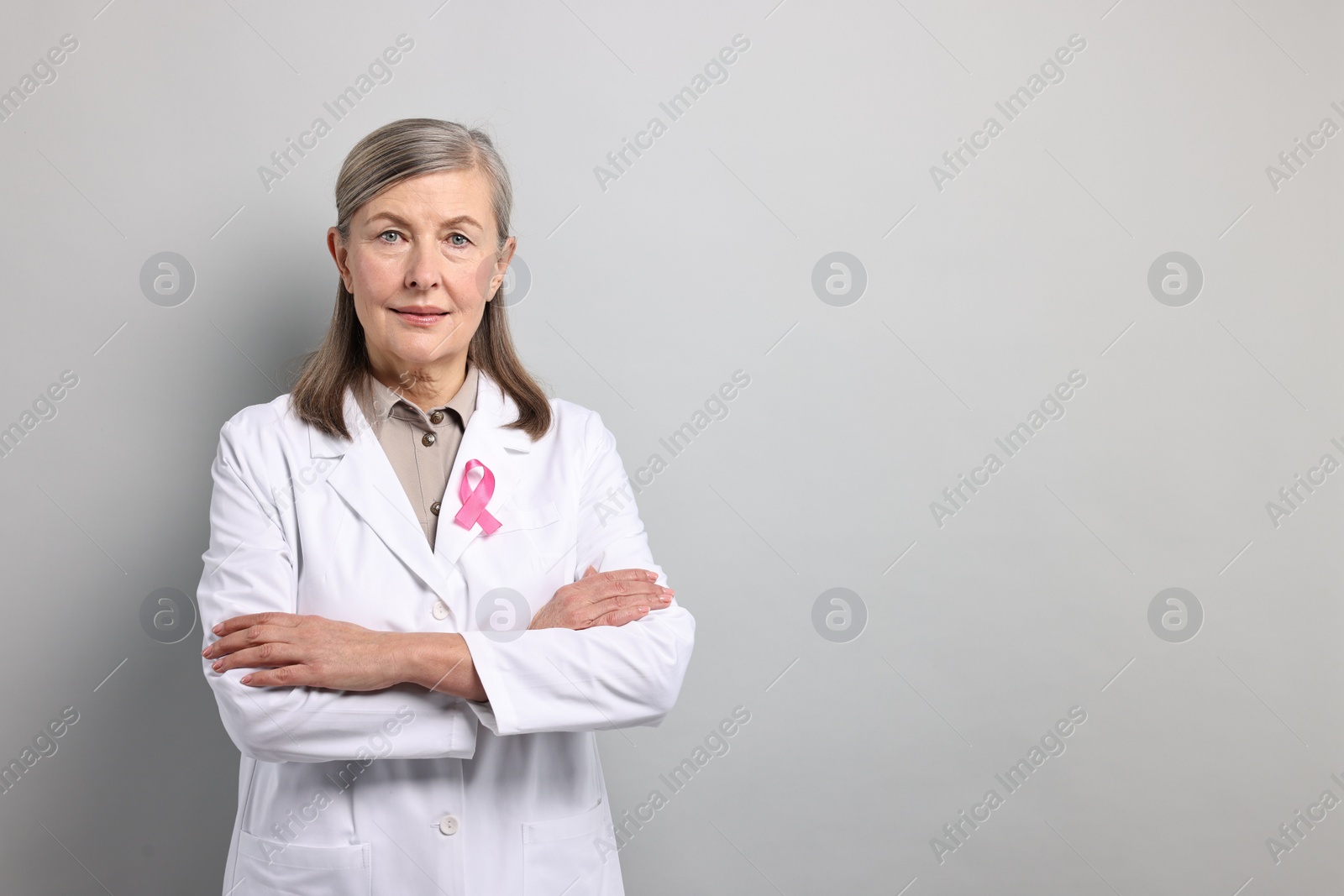 Photo of Mammologist with pink ribbon on gray background, space for text. Breast cancer awareness