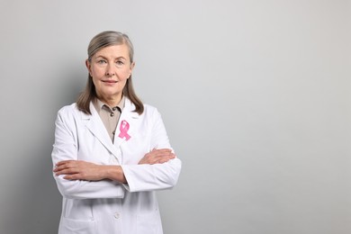 Photo of Mammologist with pink ribbon on gray background, space for text. Breast cancer awareness