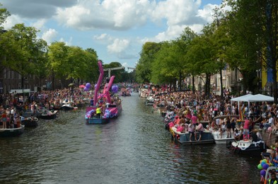 AMSTERDAM, NETHERLANDS - AUGUST 06, 2022: Many people in boats at LGBT pride parade on river