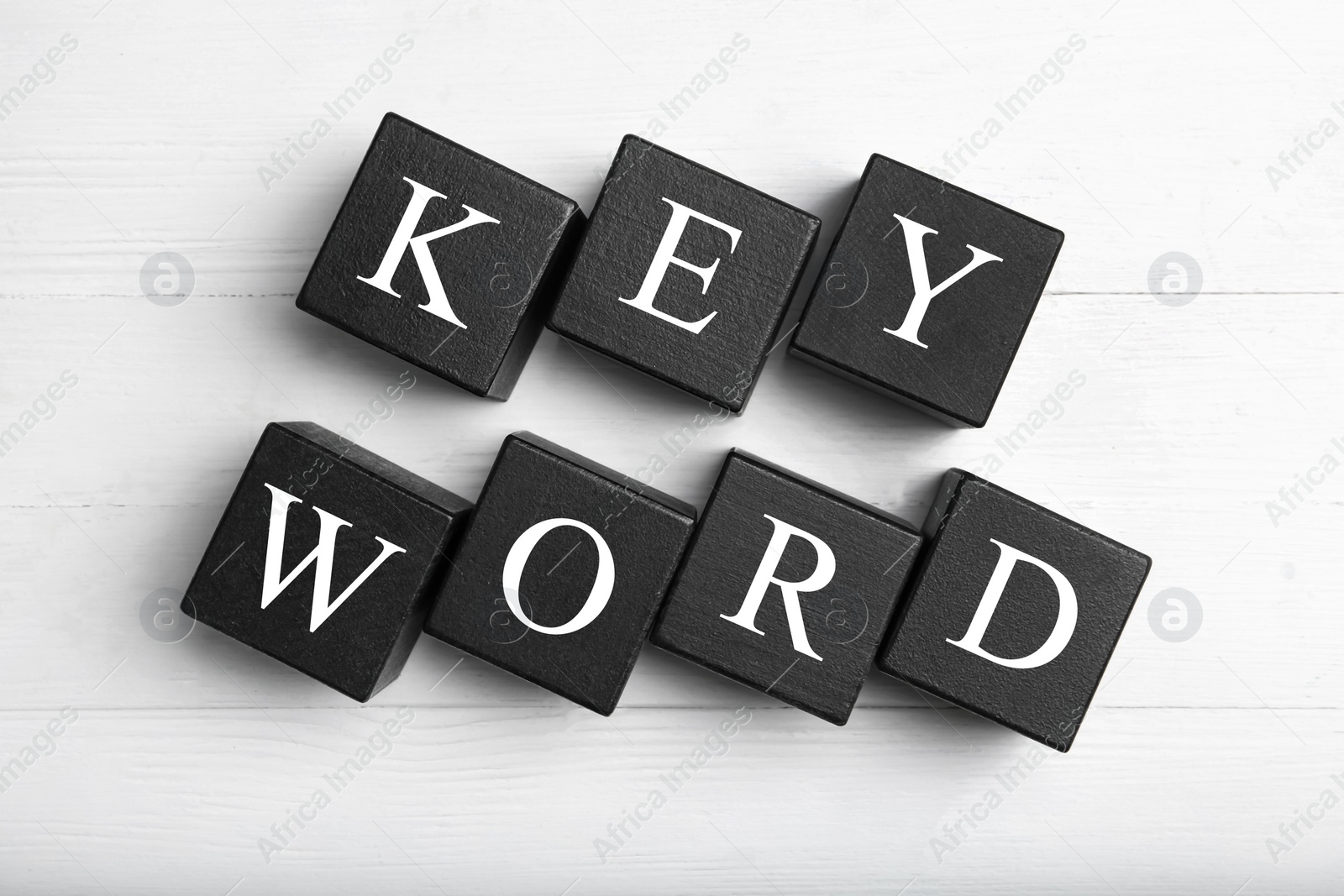 Photo of Black cubes with word KEYWORD on white wooden background, flat lay