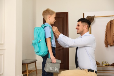 Father helping his little child get ready for school in hallway