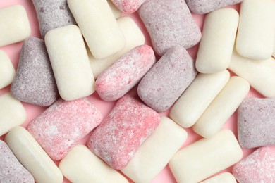 Photo of Different tasty colorful bubble gums on pink background, flat lay